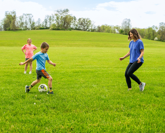 Katie, a TZIELD® (teplizumab-mzwv) patient, playing soccer with her young daughter and son outdoors