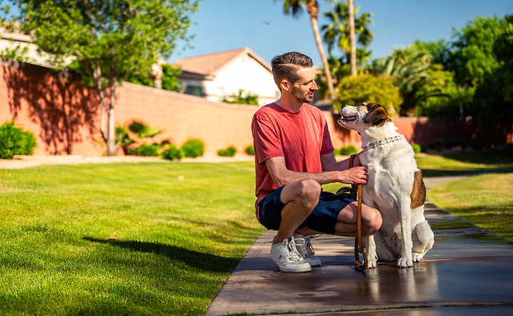 John, a TZIELD® (teplizumab-mzwv) patient, squatting down next to his dog outdoors