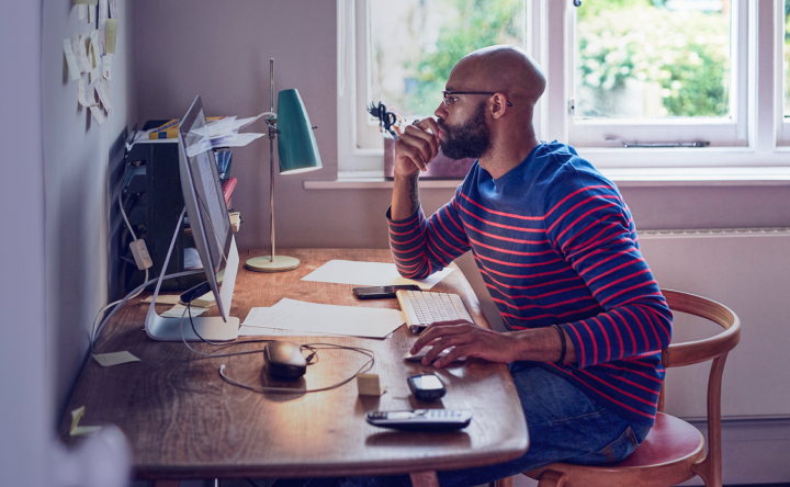A man sitting at his desk and looking at his computer screen