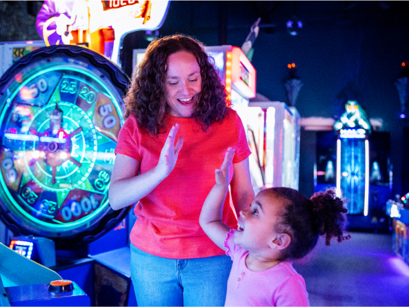Casandra, a TZIELD® (teplizumab-mzwv) patient, giving her young daughter a high five at a carnival