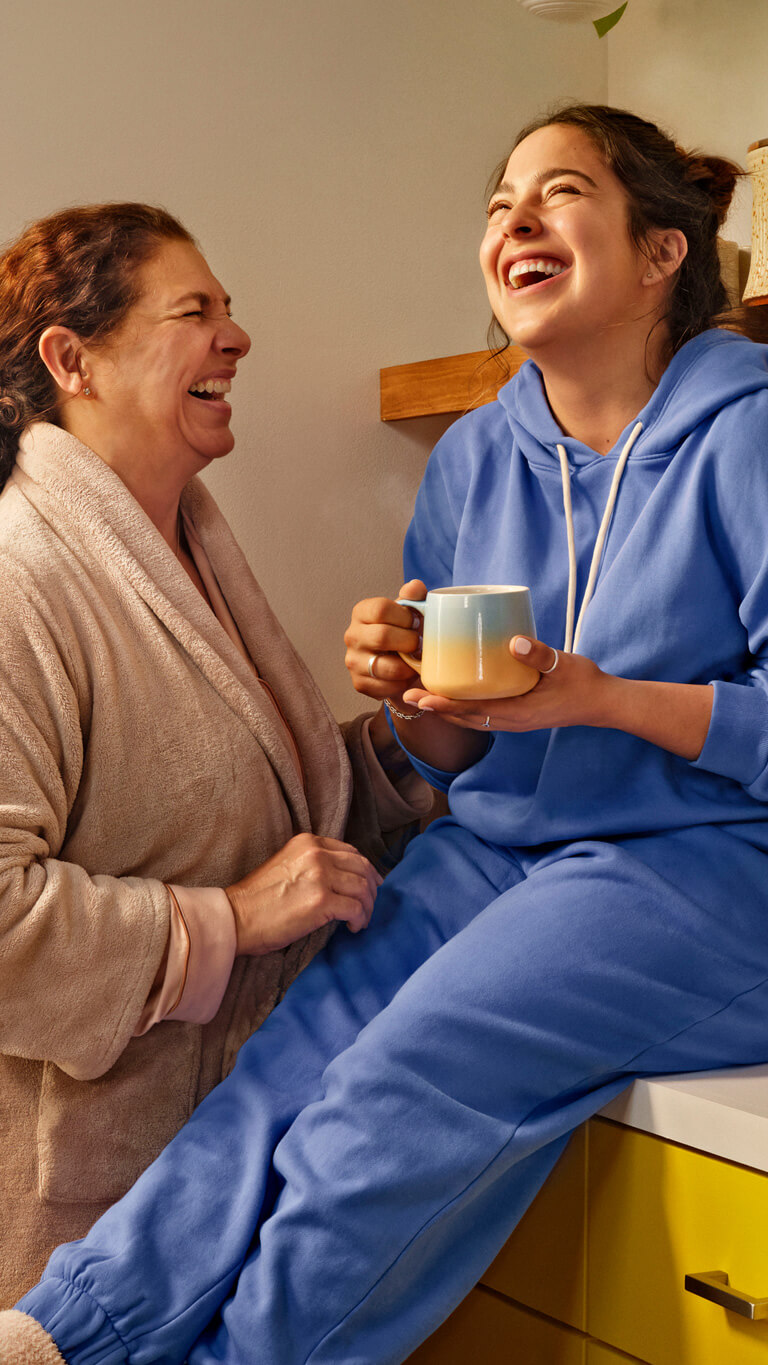 Image of a mother and young adult daughter laughing